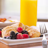 breakfast: croissant served with berries and glass of orange juice