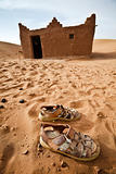 Sandals and house in Sahara desert.
