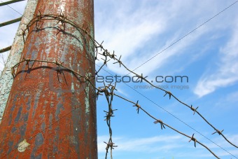 barbed wire on the pole against the blue sky