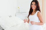 Beautiful pregnant woman holding a glass of water and pills