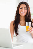 Lovely woman relaxing with her laptop while holding a glass 