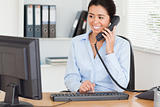 Attractive woman on the phone while typing on a keyboard