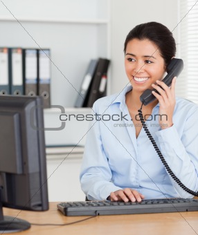 Beautiful woman on the phone while typing on a keyboard