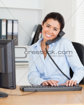 Pretty woman on the phone while typing on a keyboard