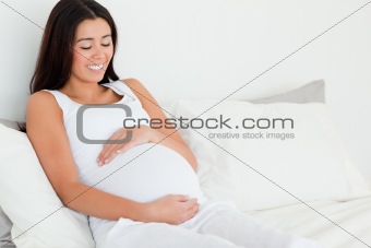Frontal view of an attractive pregnant woman touching her belly 