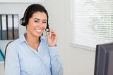 Charming woman with a headset helping customers while sitting
