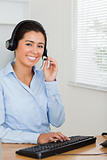 Attractive woman with a headset helping customers while sitting