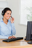 Beautiful woman with a headset helping customers while sitting