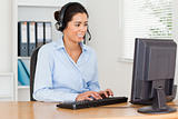 Attractive woman with a headset helping customers while typing 