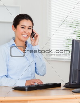 Good looking woman using her mobile phone while typing 