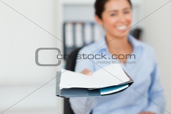 Good looking woman showing a sheet of paper to the camera