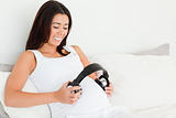 Frontal view of a beautiful pregnant woman putting headphones on