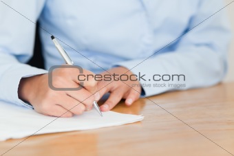 Frontal view of a young woman writing on a sheet of paper
