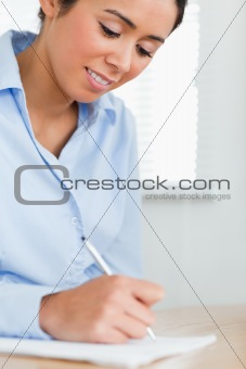 Beautiful woman writing on a sheet of paper while sitting