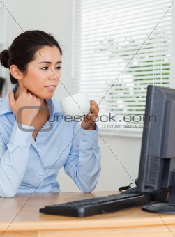 Charming woman enjoying a cup of coffee while looking at a computer