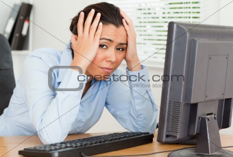 Lovely upset woman looking at a computer screen while sitting