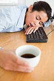 Gorgeous woman sleeping on a keyboard while holding a cup 
