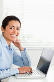 Charming woman working with her laptop and posing while sitting