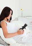 Charming pregnant woman putting headphones on her belly 