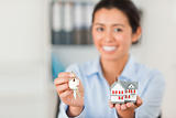 Good looking woman holding keys and a miniature house