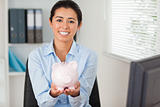 Beautiful woman holding a piggy bank while looking at the camera