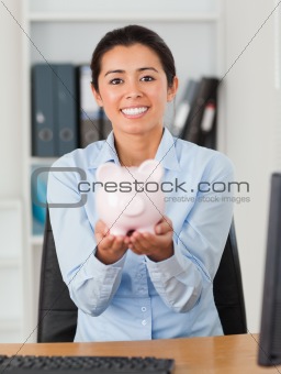 Good looking woman holding a piggy bank while looking at the camera