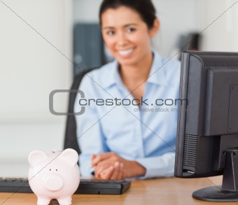 Beautiful woman posing with a piggy bank in front of her