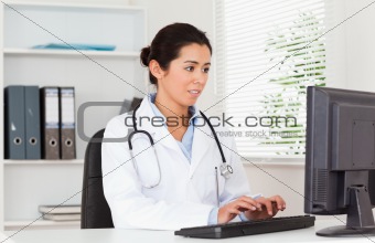 Gorgeous female doctor typing on a keyboard while sitting