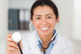 Attractive female doctor using a stethoscope while looking