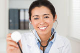 Beautiful female doctor using a stethoscope while looking 