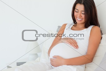 Gorgeous pregnant woman posing while lying on a bed