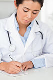 Beautiful female doctor writing on a scratchpad