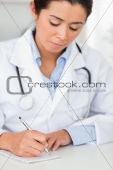 Beautiful female doctor writing on a scratchpad