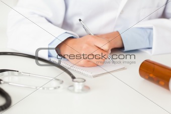 Young female doctor writing on a scratchpad
