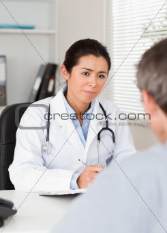 Pretty female doctor listening carefully to a patient