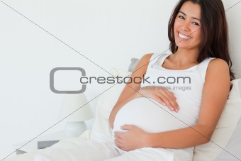 Beautiful pregnant woman posing while lying on a bed