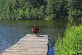 Elderly woman fishing from the dock. 