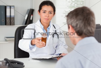 Beautiful female doctor showing a box of pills to the camera