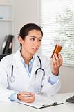 Beautiful worried doctor holding a box of pills