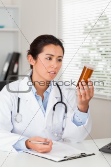 Beautiful worried doctor holding a box of pills