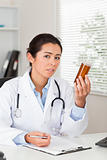 Pretty worried doctor holding a box of pills
