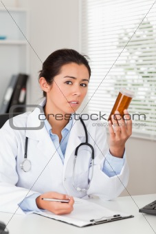Pretty worried doctor holding a box of pills