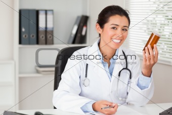 Attractive smiling doctor holding a box of pills