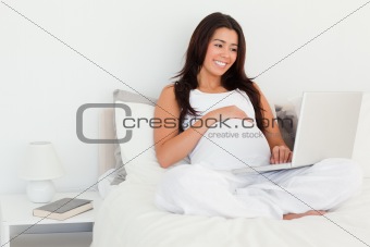 Beautiful pregnant woman relaxing with her laptop 