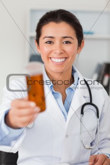 Portrait of an attractive smiling doctor holding a box of pill