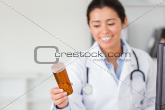 Attractive smiling doctor holding and looking at a box of pills