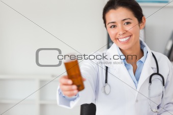 Pretty smiling doctor holding a box of pills