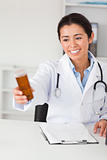 Lovely smiling doctor holding a box of pills while sitting