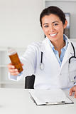 Beautiful smiling doctor holding a box of pills while sitting