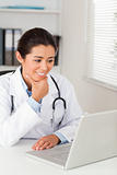 Beautiful female doctor working with her laptop while sitting